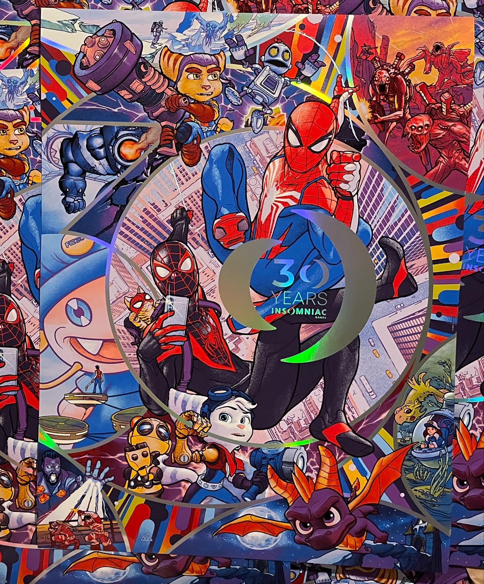 Photo of Insomniac Games 30th Anniversary 13 color silkscreen printed poster with artwork by Martin Ansin and published by Plush Art Club. It features various games develo sped by Insomniac Games: Marvel's Spider-Man, Spyro the Dragon, Resistance, Song of the Deep, Fuse / Overstrike, Ratchet and Clank, Edge of Nowhere, Sunset Overdrive, and Disruptor. Characters features are Peter Parker, Miles Morales, Fizzie, Ratchet, Clank, Rivet, Kit, Spyro, Merryn, Chimeras, among others. It is officially-licensed.